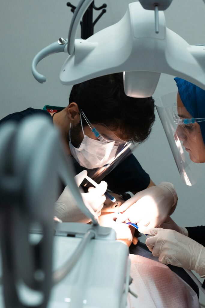 Especialidades Disponibles Dentists performing a precise dental procedure in a well-equipped clinic.